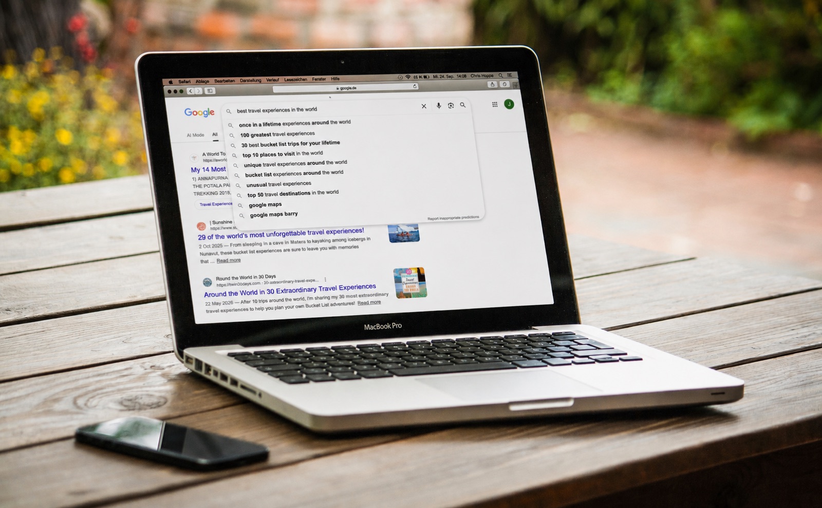 A traveller searching Google for the best travel experiences in the world, with autocomplete suggestions and search results on a MacBook