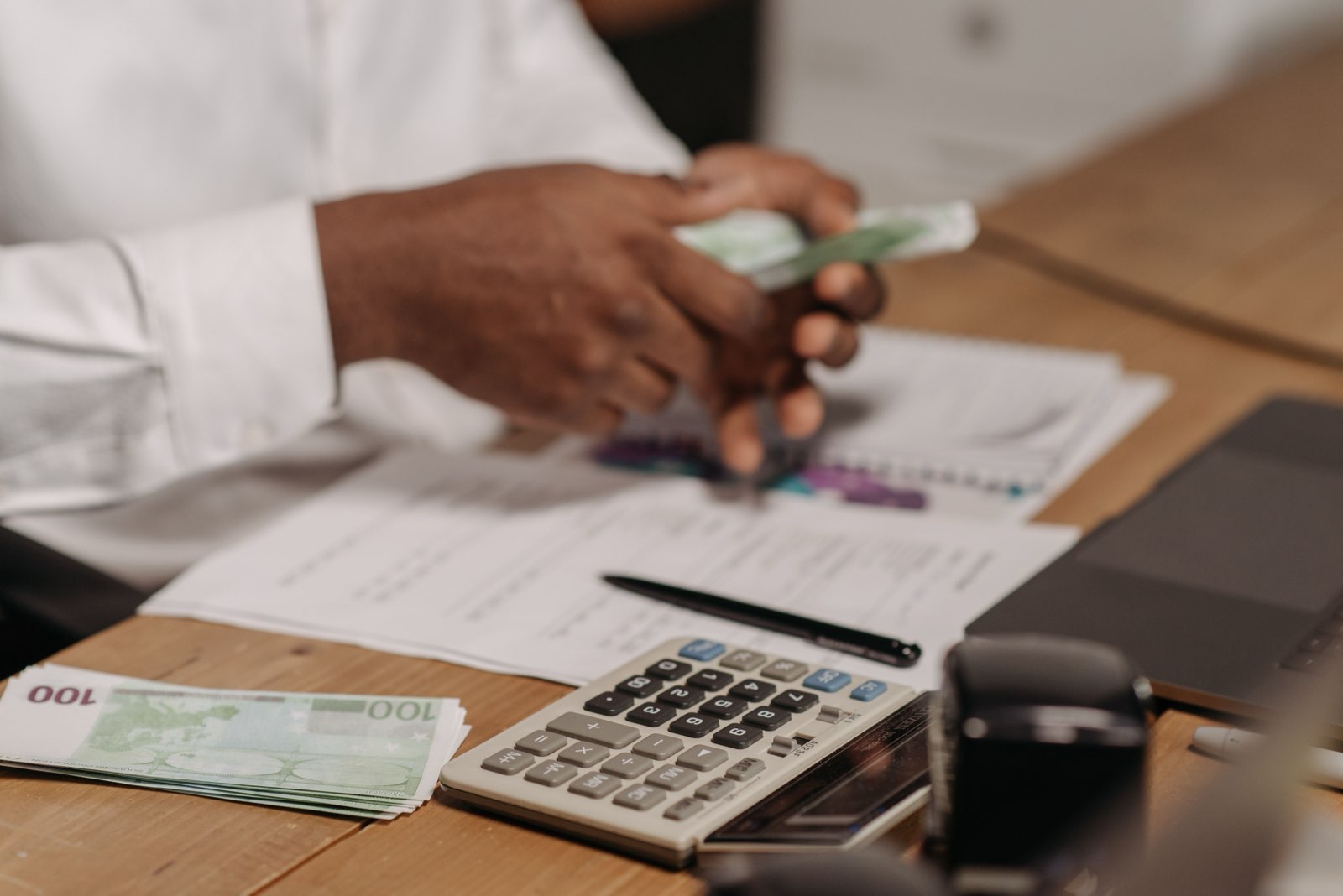 Calculator, pen and euro notes on a desk, representing OTA commission costs